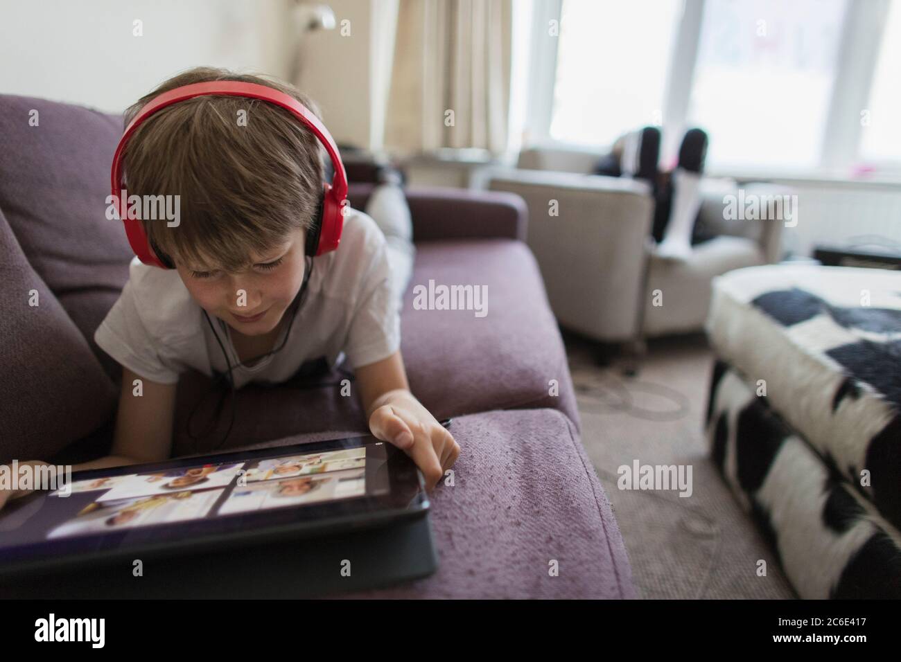 Garçon avec casque et tablette numérique homeschooling sur le canapé Banque D'Images