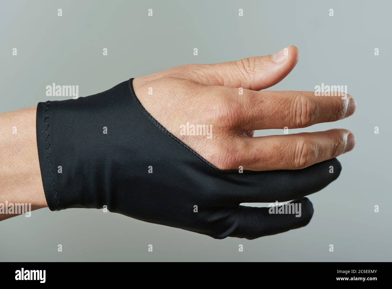 gros plan d'un homme caucasien portant un gant noir à deux doigts sur un fond gris Banque D'Images