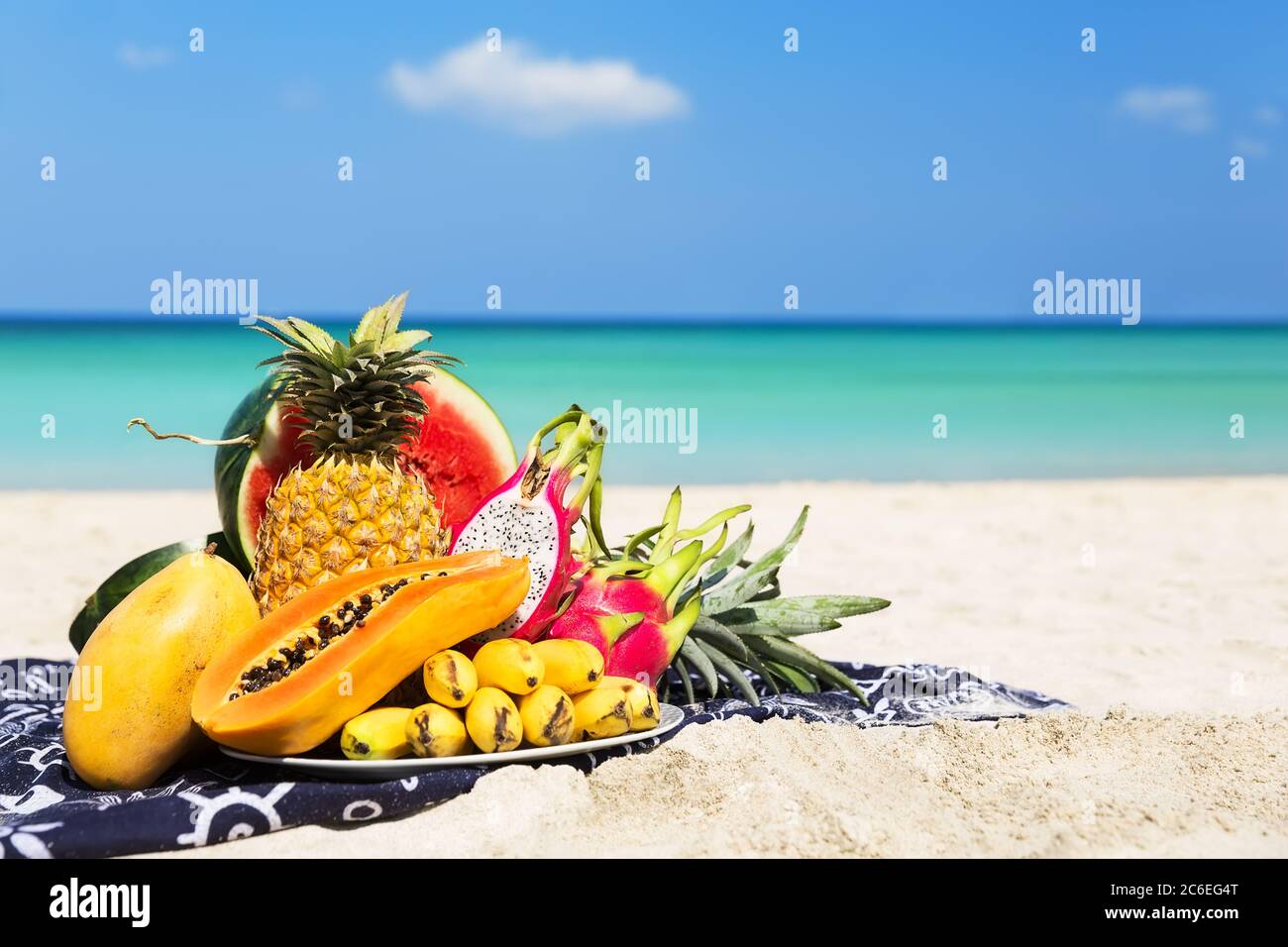 Fruits tropicaux frais différents placés sur l'assiette avec ciel bleu et mer comme fond. Concept de l'été d'une alimentation saine. Banque D'Images