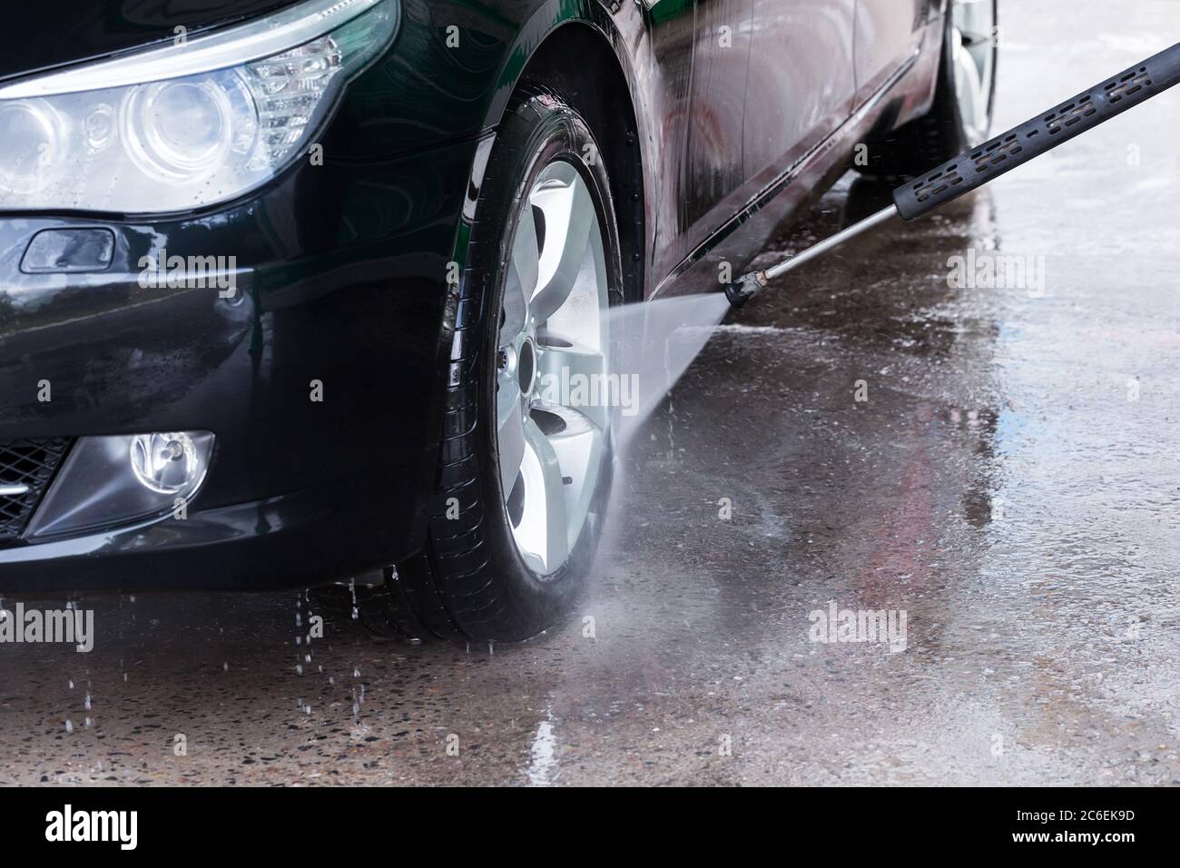 Nettoyage de la voiture noire avec de l'eau haute pression. Lavage manuel de voiture avec eau sous pression dans le lavage de voiture extérieur. Banque D'Images