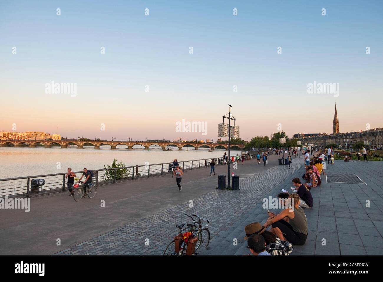 Promenade le long de la rivière Garrone avec randonneurs et cycliste au coucher du soleil, Bordeaux, France Banque D'Images