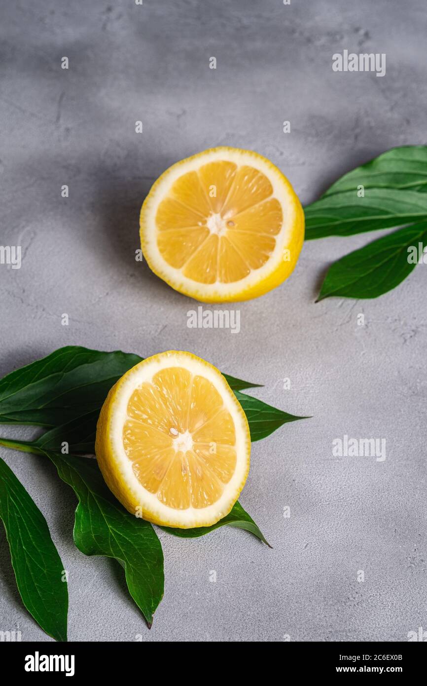 Deux tranches de citron, agrumes tropicaux avec feuilles vertes sur fond de béton gris, vue en angle Banque D'Images