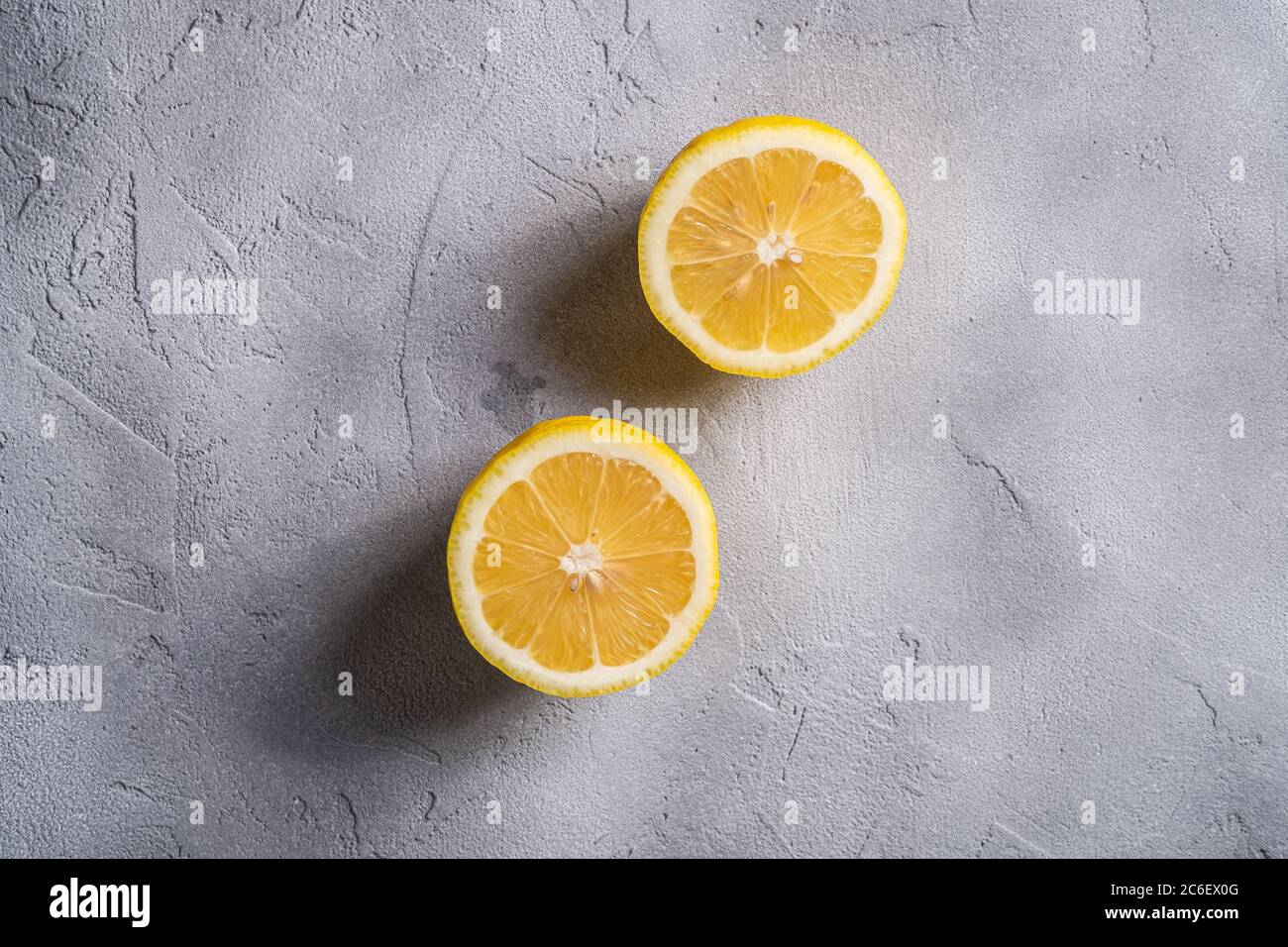 Deux tranches de citron, agrumes tropicaux sur fond de béton gris, vue du dessus Banque D'Images