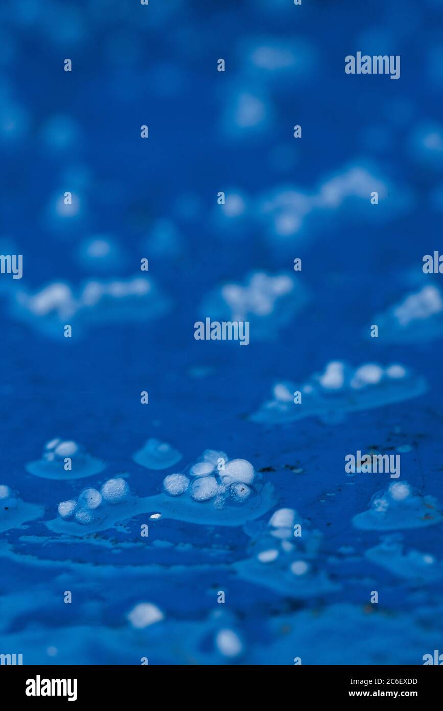 Pierres à grêle capturant des particules noires de pollution de l'atmosphère au-dessus de Londres sur un fond bleu vif. Banque D'Images