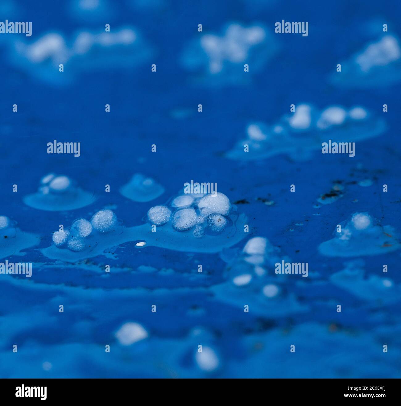 Pierres à grêle capturant des particules noires de pollution de l'atmosphère au-dessus de Londres sur un fond bleu vif. Banque D'Images