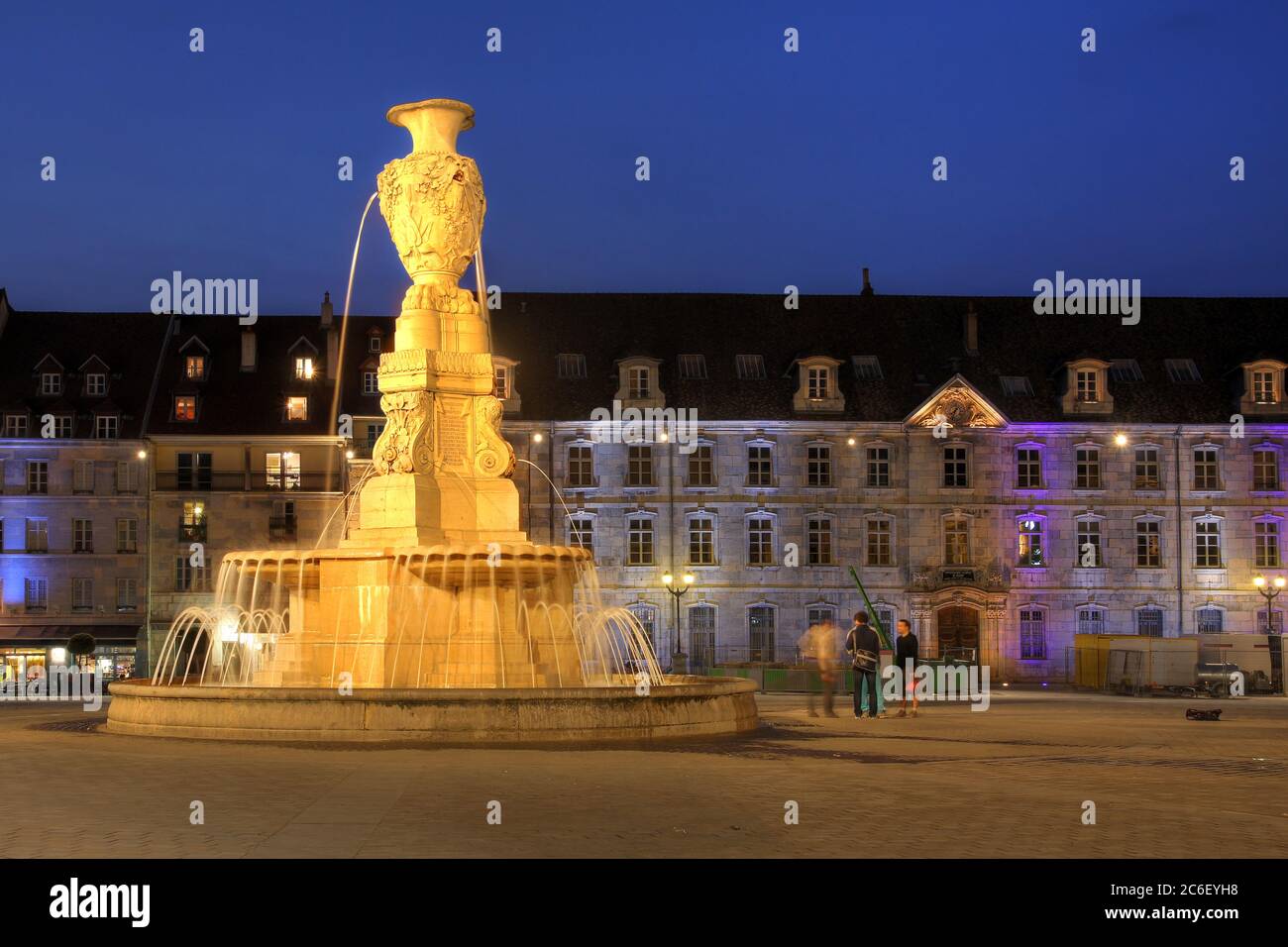 Une fontaine dans la place de la Révolution à Besançon, en France, la nuit, avec le Conservatoire de la ville en arrière-plan. Banque D'Images