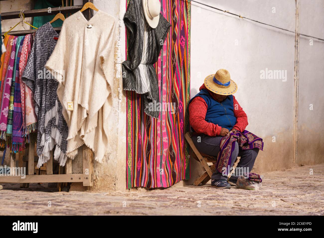 Une vieille dame autochtone dormant dans la rue à côté de son magasin de vêtements tout en triant un vêtement Banque D'Images