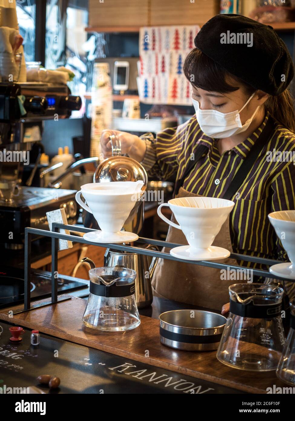 Nagoya, Aichi, Japon - Femme Barista portant un masque. Faire verser sur le café dans le café Kannon. Populaire pour le café goutte-à-goutte, les biscuits et les bonbons mignons. Banque D'Images