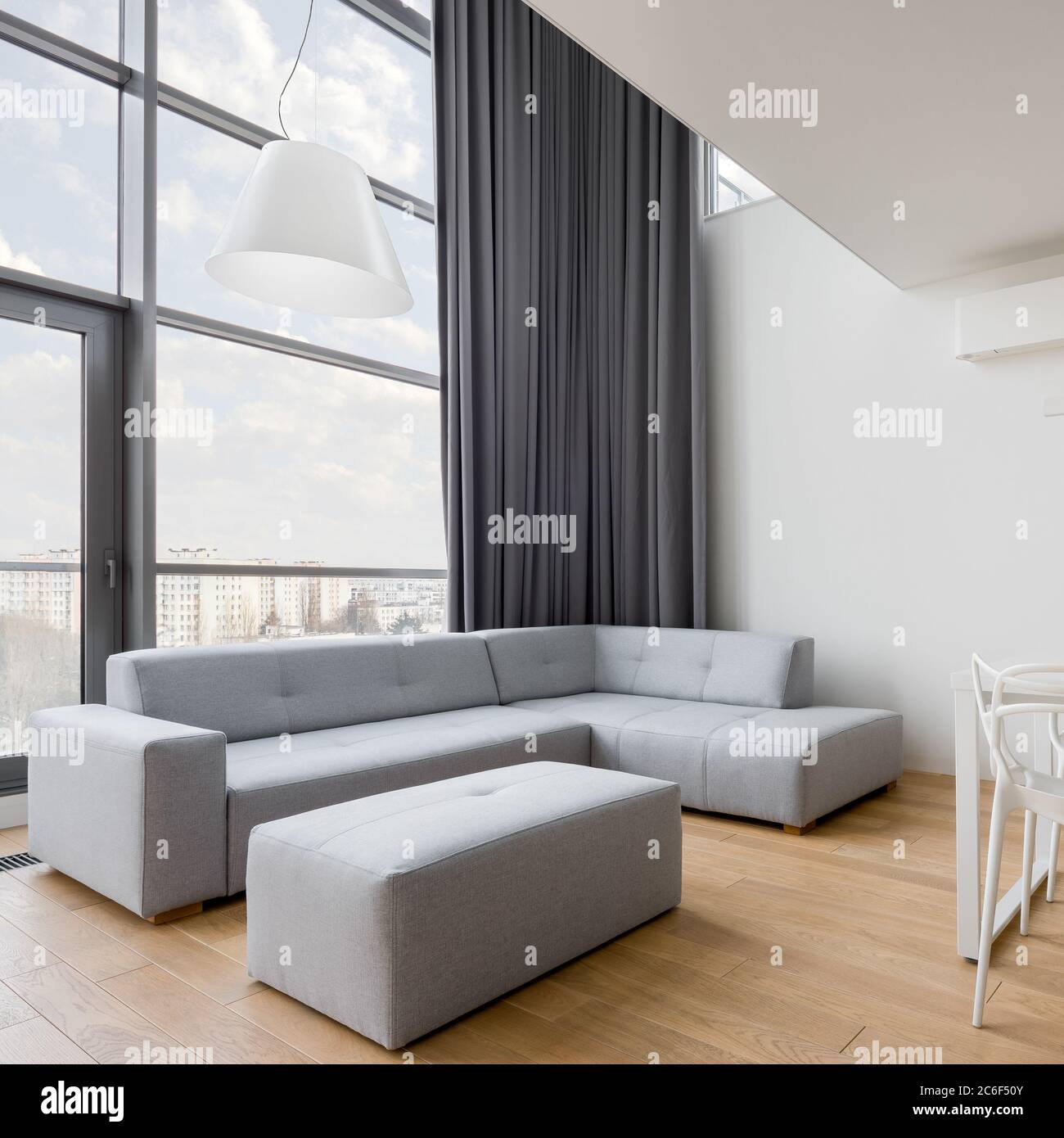 Salon contemporain avec canapé d'angle gris et grande fenêtre Banque D'Images