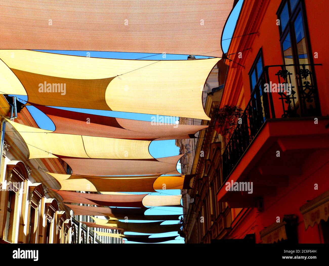 Tente et auvent colorés et bien taillés voile soleil voile protection UV  tissu suspendu de l'extérieur au-dessus de la rue urbaine. Centre-ville de  la vieille ville. Protection contre le soleil Photo Stock -