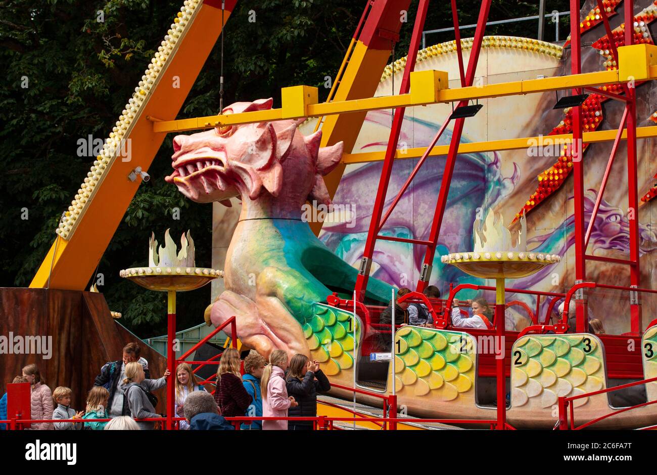 Les gens en file d'attente à bord du gros dragon tête balancer navire viking au funfair dans un parc d'attractions public. Les clients balancent comme un pendule de la dra Banque D'Images