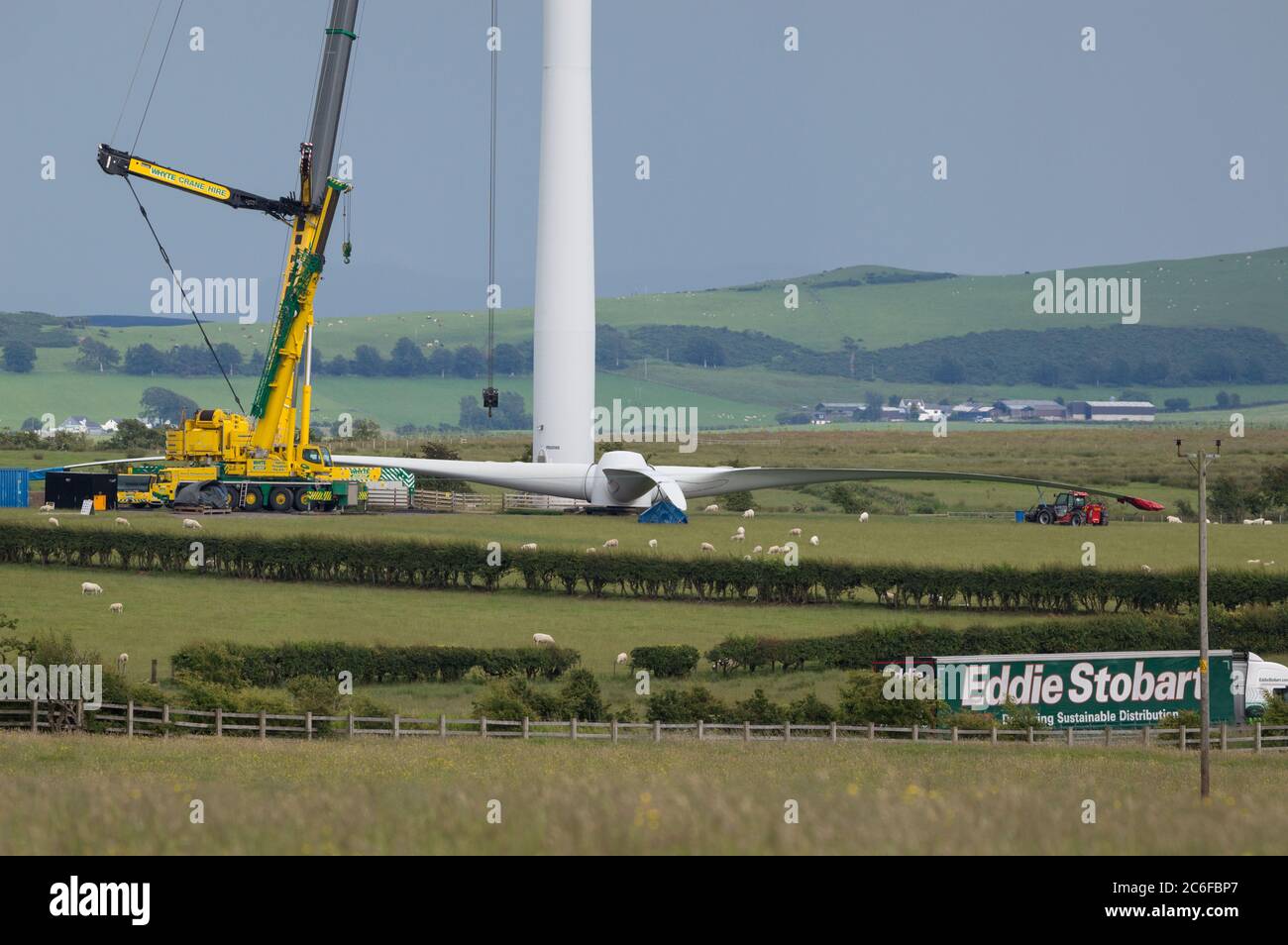 Larkhall, Écosse, Royaume-Uni. 9 juillet 2020. Photo : une énorme éolienne mesure quelques centaines de pieds tandis que ses pales reposent sur le sol, prêt à être fixé. L'énergie verte est une grande affaire, et si le Royaume-Uni doit archiver ses objectifs en matière d'énergie renouvelable, il faut construire davantage d'éoliennes à terre et en mer. Crédit : Colin Fisher/Alay Live News Banque D'Images