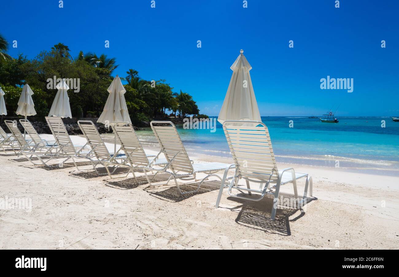 un groupe de chaises de plage vides invitant pour un bain de soleil sur une plage blanche en face de l'eau claire en cristal dans les caraïbes Banque D'Images