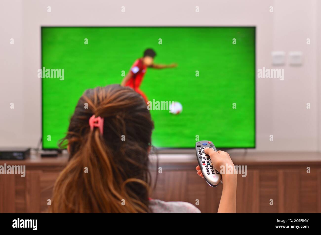 Les femmes regardent un match de football à la télévision et utilisent la télécommande Banque D'Images