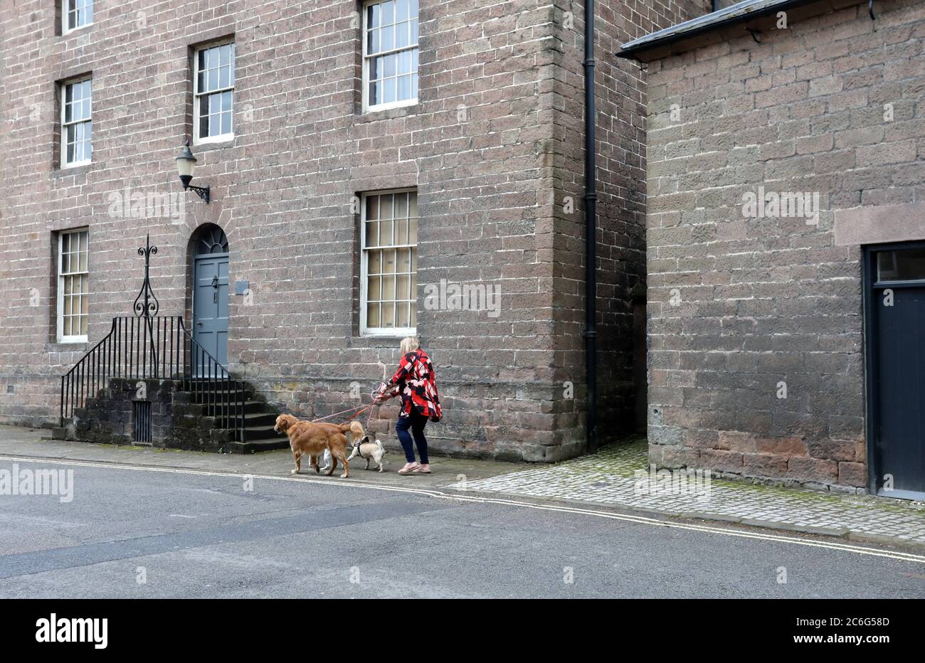 Marcheur de chiens passant devant l'ancienne maison des gestionnaires sur Mill Lane à Cromford Mill site du patrimoine mondial dans le Derbyshire Banque D'Images