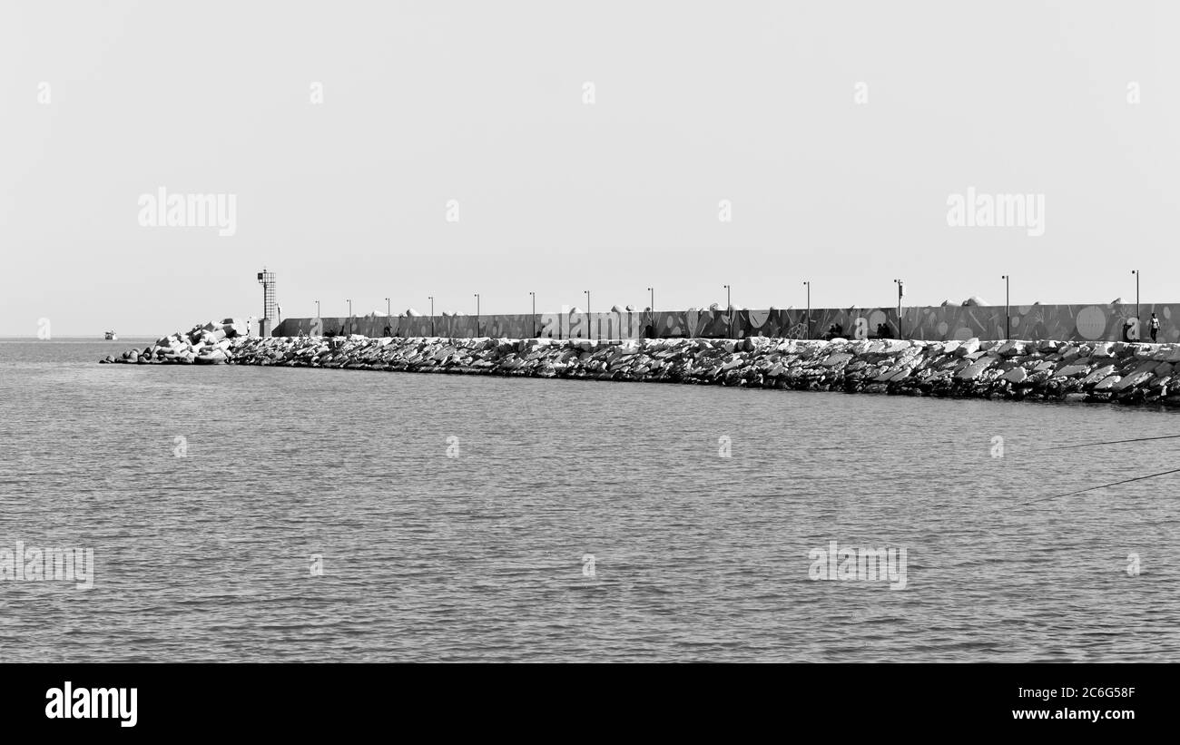 La jetée du port de Pesaro avec des falaises de brise-lames, un mur coloré et un petit phare rouge (Marche, Italie, Europe) Banque D'Images