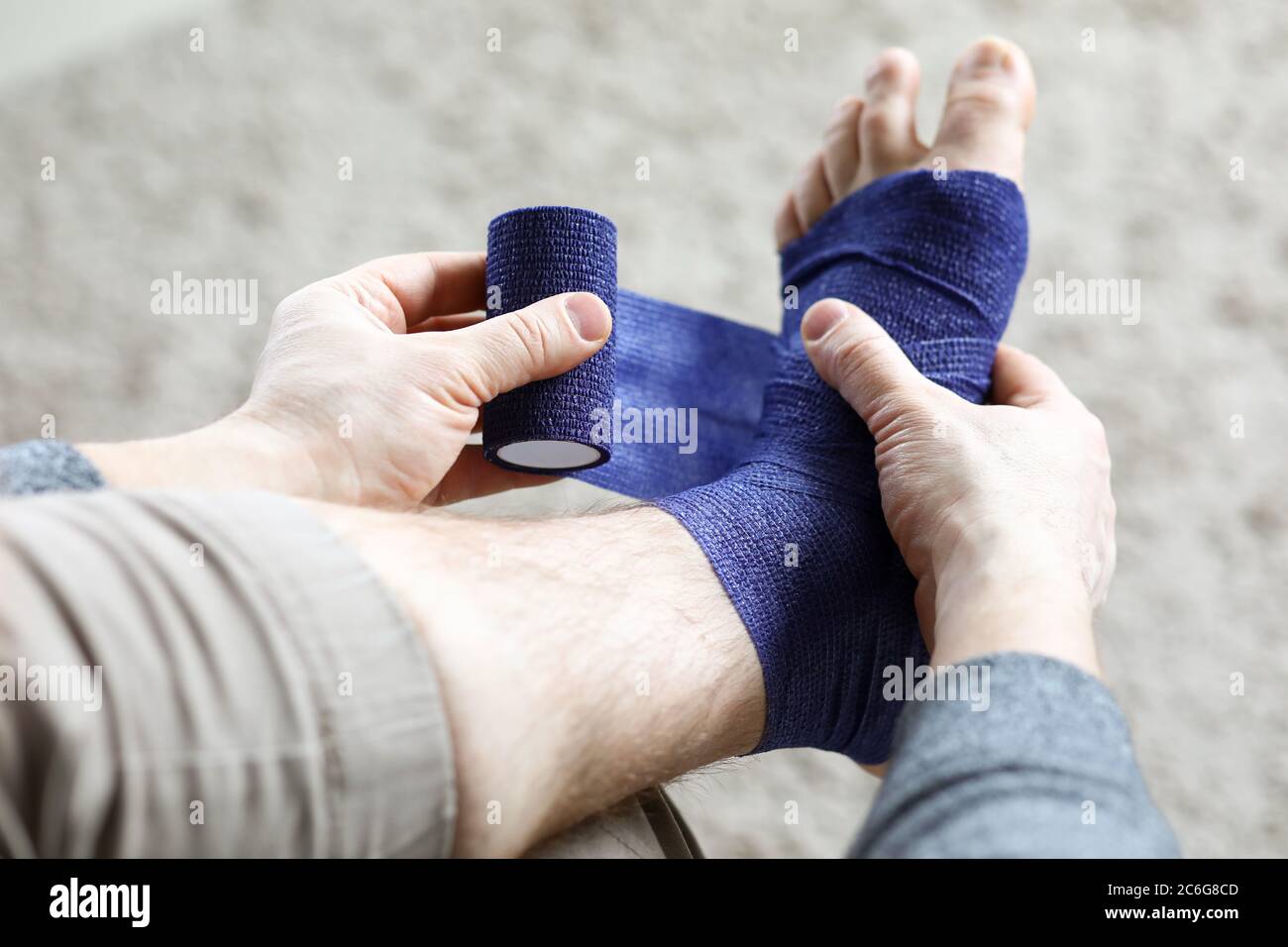 L'homme tire sur sa jambe avec un bandage élastique Banque D'Images