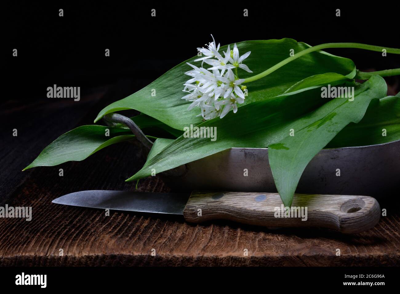 Feuilles d'ail sauvage et fleur dans un bol et un couteau de cuisine, Allemagne Banque D'Images