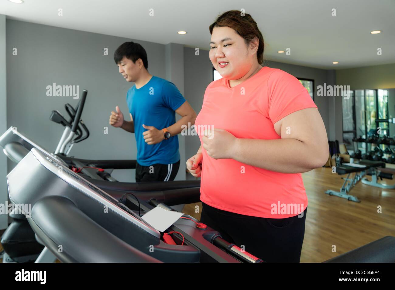Deux formateurs de l'Asie et de l'embonpoint homme femme l'exercice de formation sur tapis roulant dans une salle de sport, formateur thump vers elle pour bon résultat lors de l'entraînement. Grosses Femmes Banque D'Images
