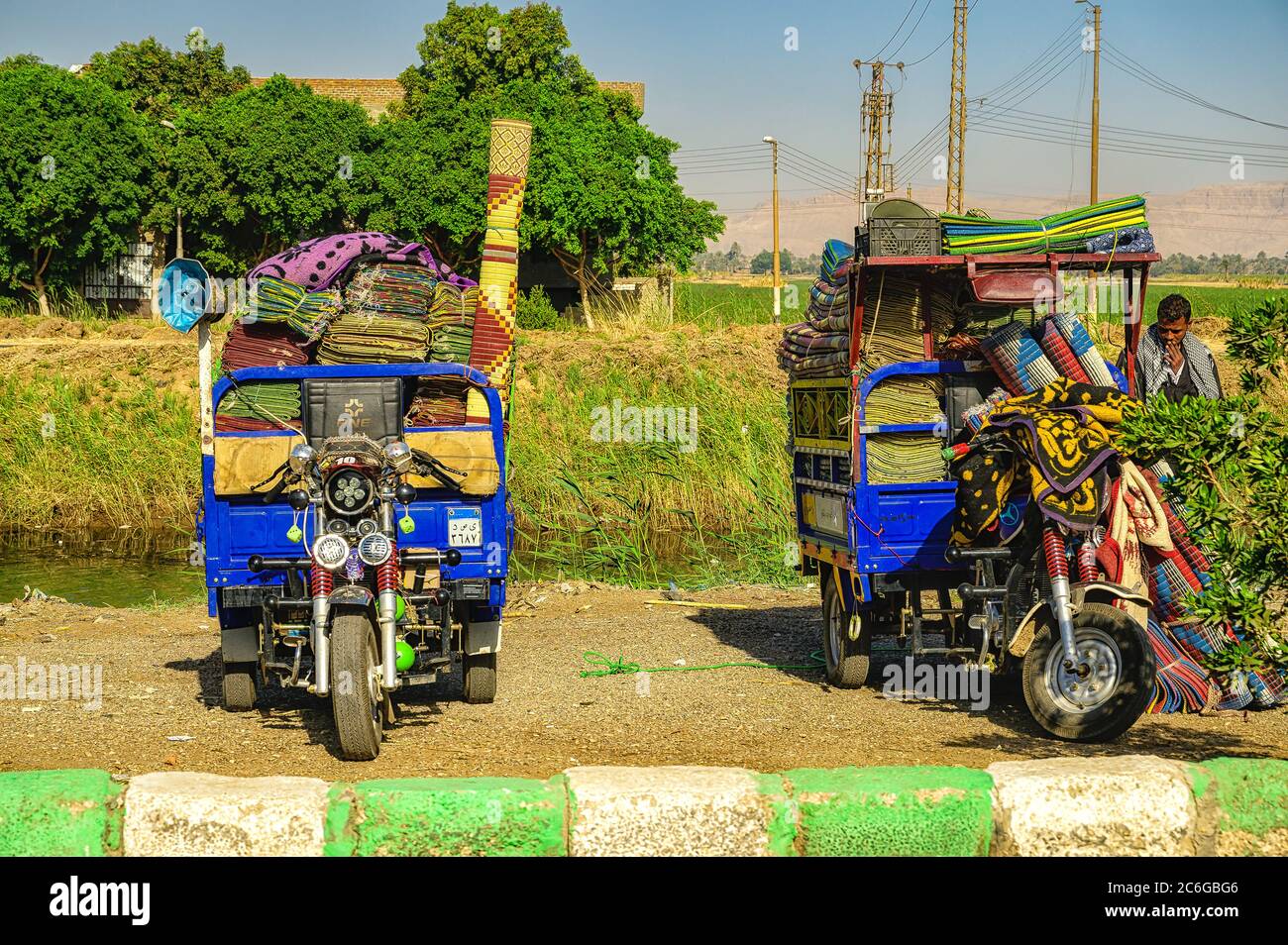 Les vendeurs de tapis sont garés sur le côté de la route à Louxor, à côté de leurs Tuk Tuks aux couleurs vives Banque D'Images