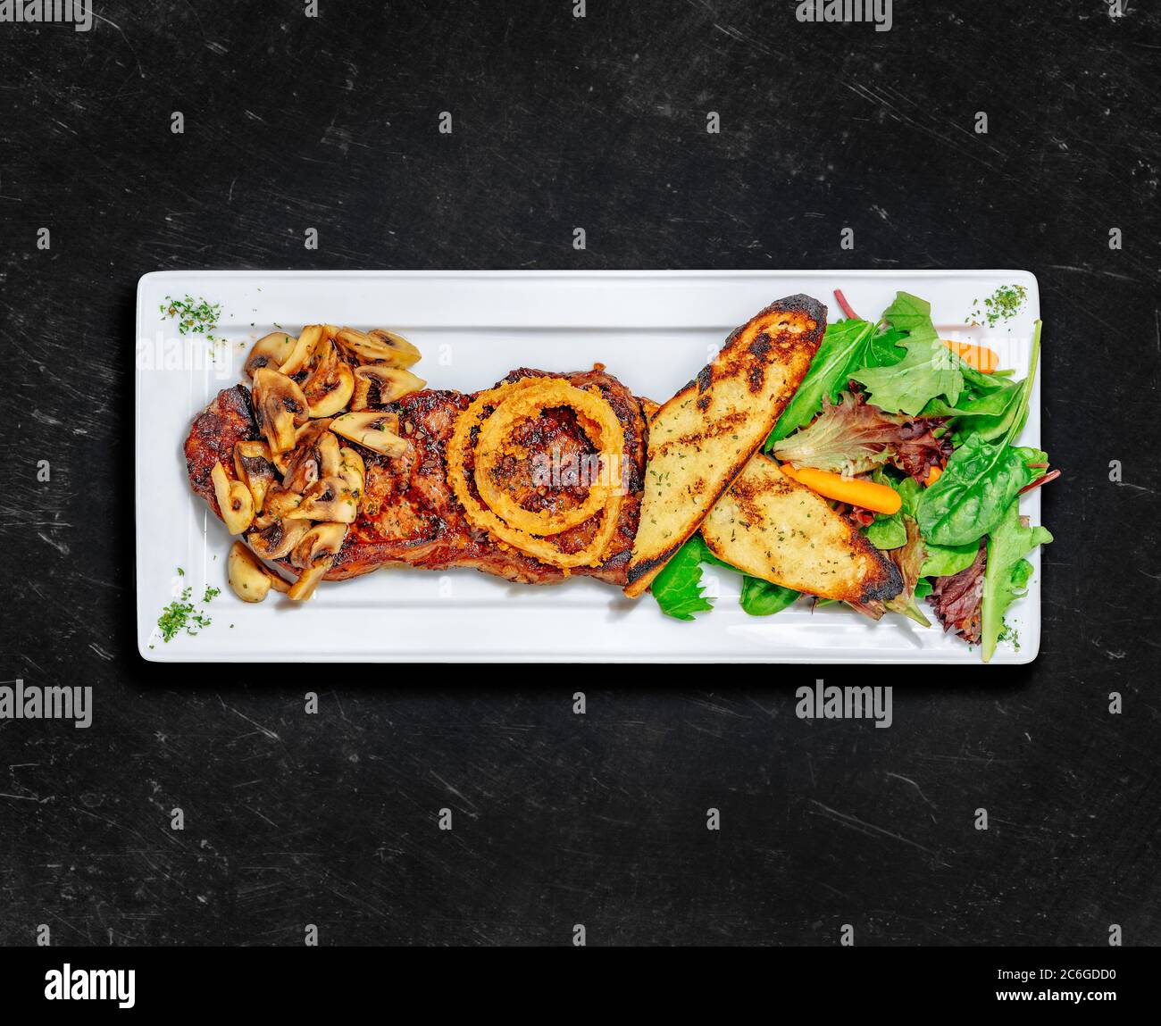 Steak de striploin de New York. Une alimentation saine. Steak grillé servi avec deux côtés, toasts à l'ail, champignons et salade. Arrière-plan craché. Vue de dessus Banque D'Images