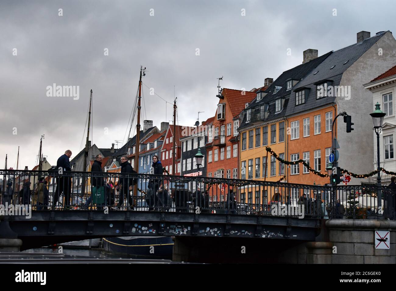 Les maisons de ville colorées sur le côté nord du canal de Nyhavn derrière le pont. Les mâts des voiliers peuvent également être vus contre le ciel gris. Banque D'Images