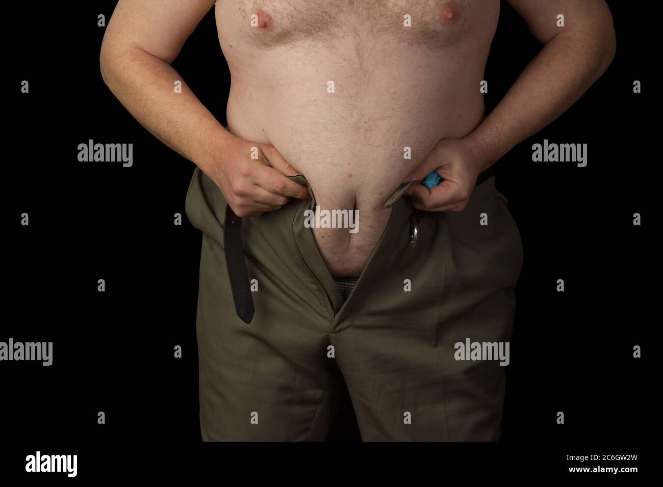 Un homme en surpoids ne peut pas serrer son pantalon parce que ses graisses  dans le ventre Photo Stock - Alamy