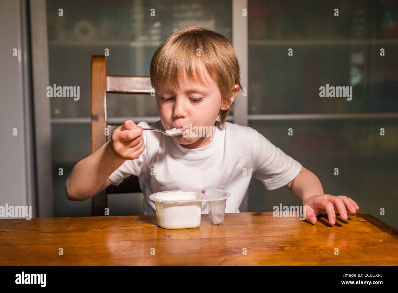 Adorable petite fille mangeant du fromage cottage de la cuillère, en-cas de lait sain. Banque D'Images