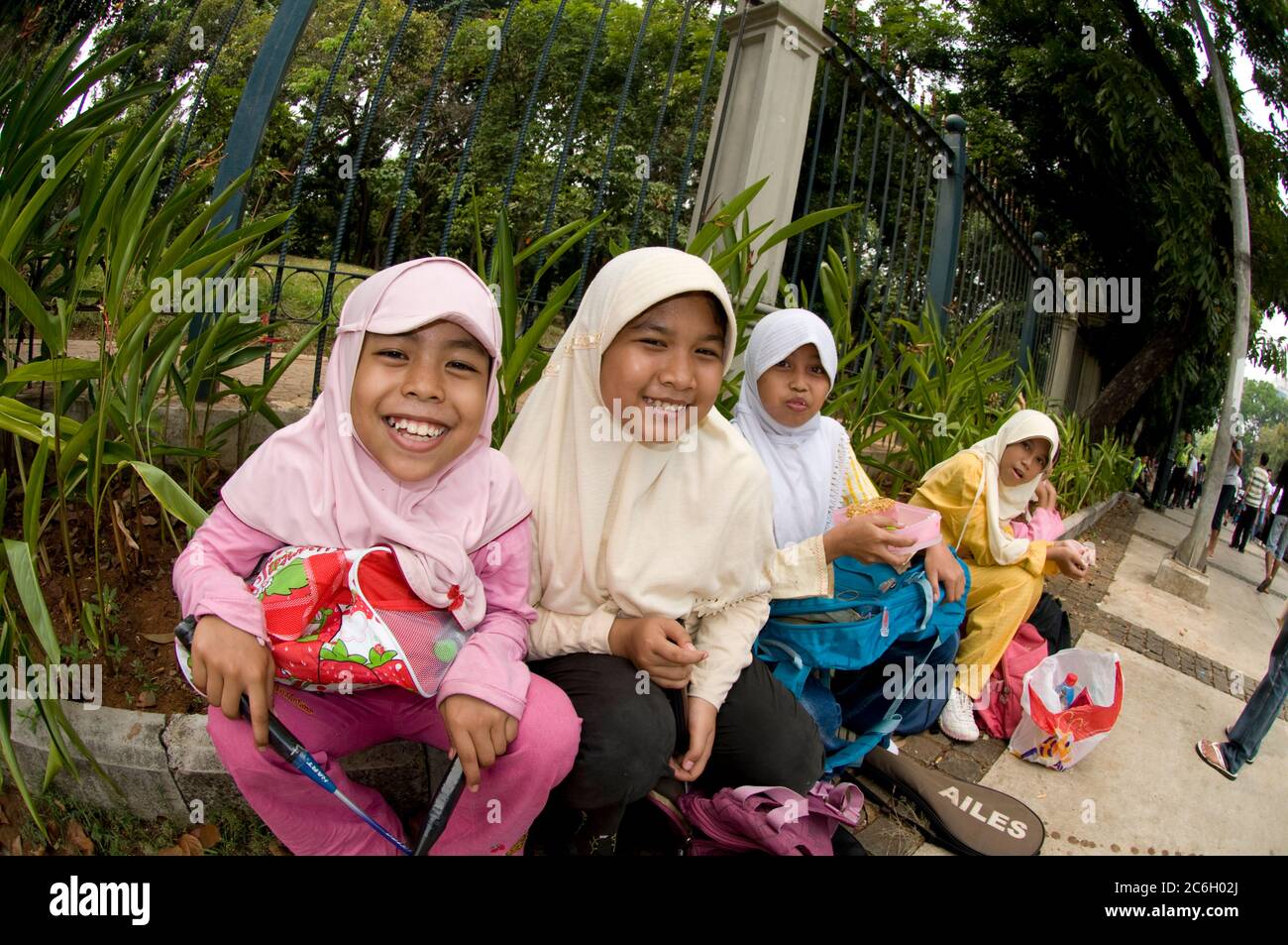Filles musulmanes avec raquettes de badminton assises sur la chaussée, Jakarta, Indonésie Banque D'Images
