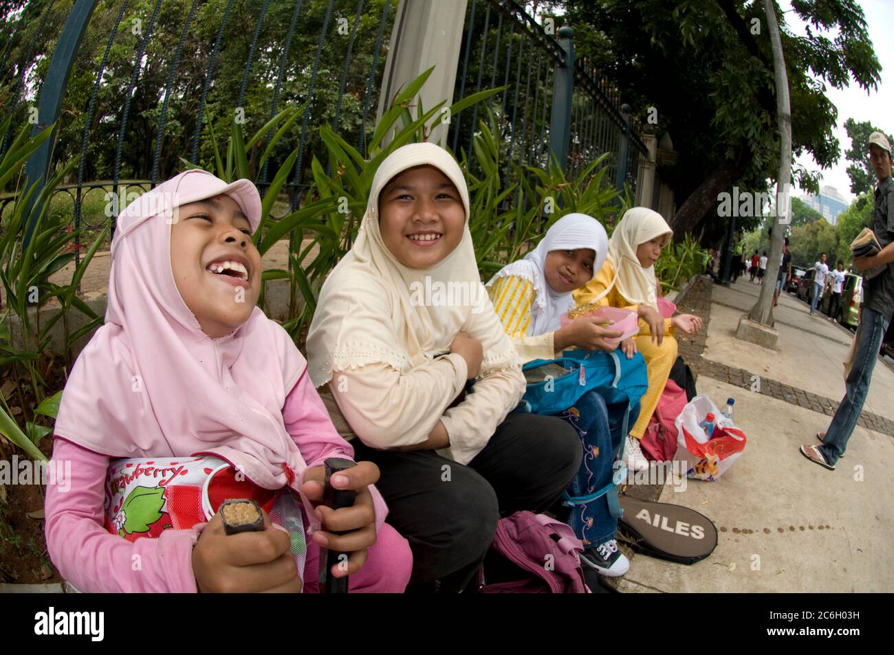 Rire de fille musulmane avec des raquettes de badminton assis sur le trottoir, Jakarta, Indonésie Banque D'Images