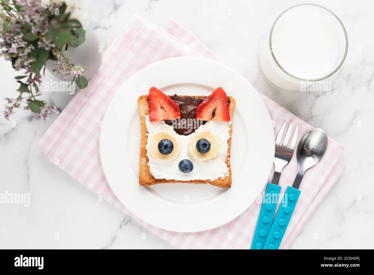 Toast pour le petit déjeuner pour les enfants en forme d'animal mignon avec tartinade chocolat aux noisettes, fromage à la crème et baies servis avec un verre de lait. Vue de dessus. Chi Banque D'Images