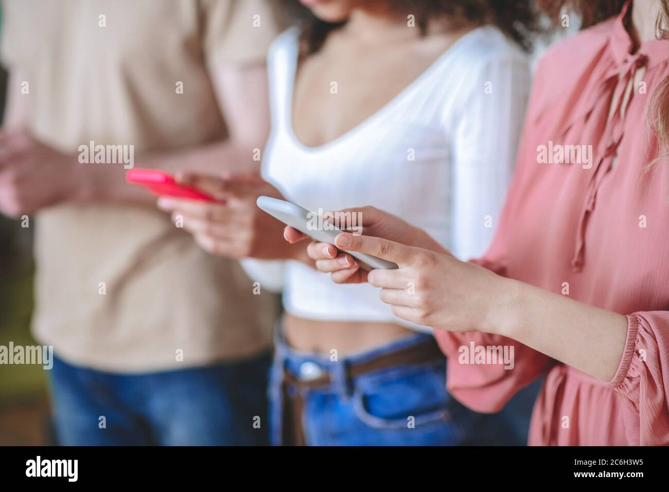 Mains de deux filles et gars tenant des smartphones, sans visage Banque D'Images