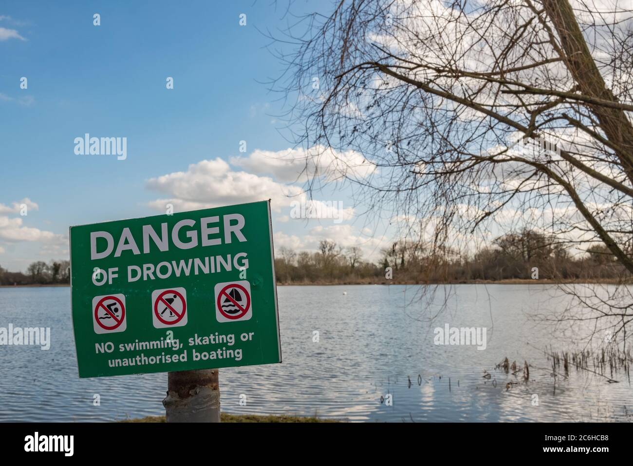 Vue détaillée d'un danger de noyade panneau voir placé près d'un grand et profond lac intérieur en Angleterre. Vue au coucher du soleil près des roseaux. Banque D'Images