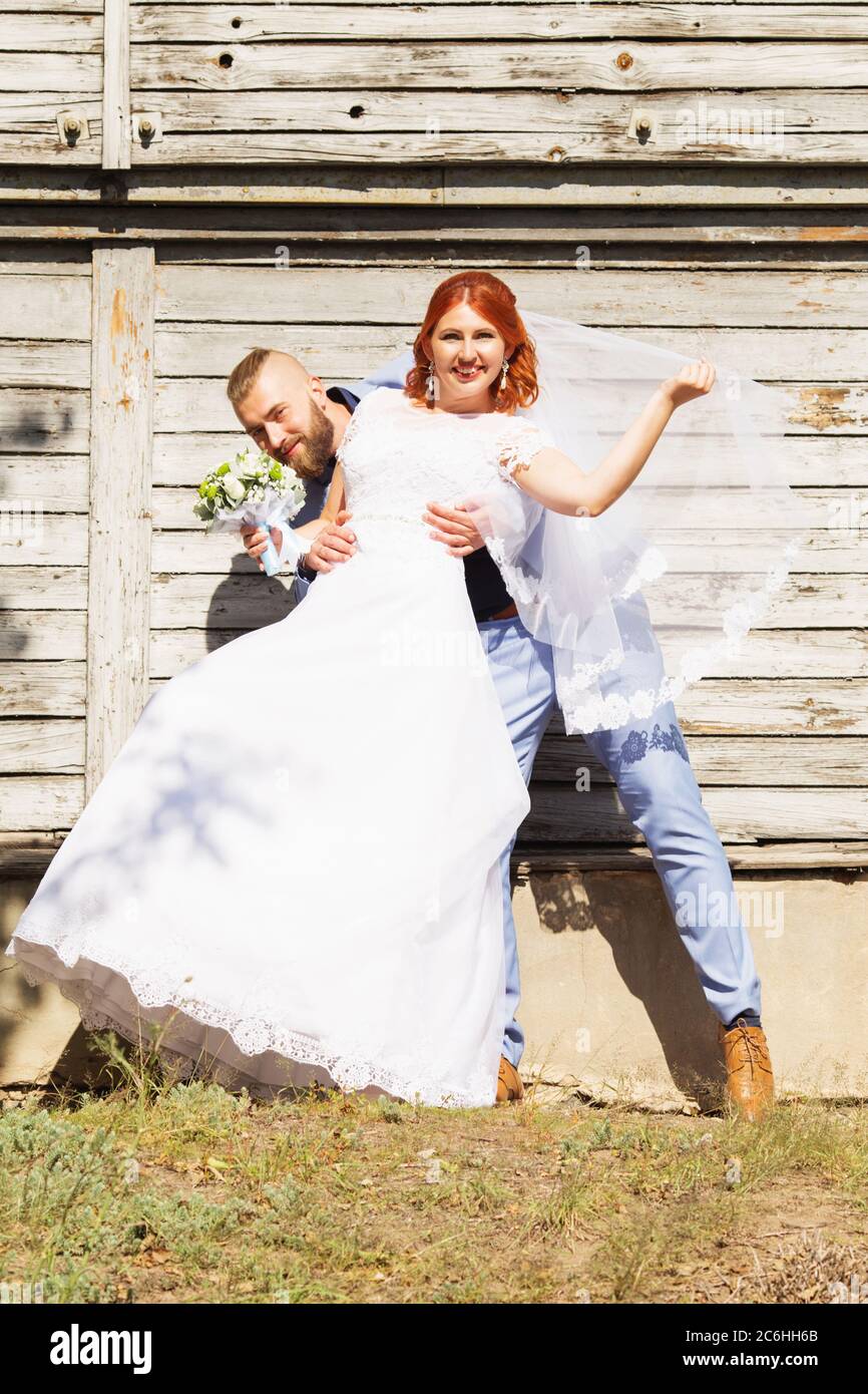 Juste marié aimant hipster couple dans la robe de mariage et le costume  posant en face d'une vieille maison en bois. Bonne mariée et marié marchant  et dansant Photo Stock - Alamy