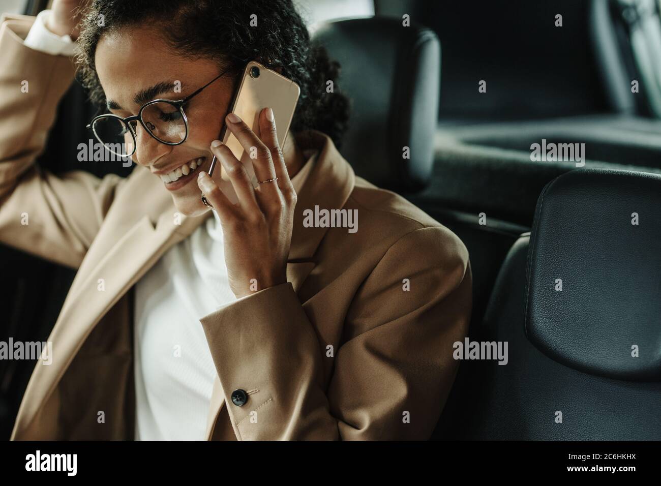 Femme d'affaires assise dans sa voiture et parlant au téléphone. Femme en tenue d'affaires qui fait un appel téléphonique en étant assise dans sa voiture. Banque D'Images