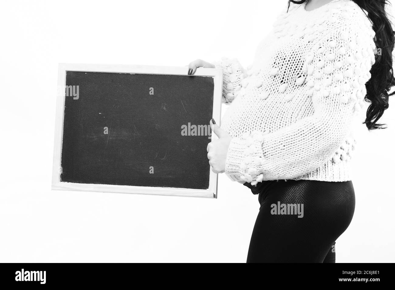 mains féminines de la femme enceinte tenant un pull en tricot noir beige isolé sur fond de studio blanc, espace de copie Banque D'Images