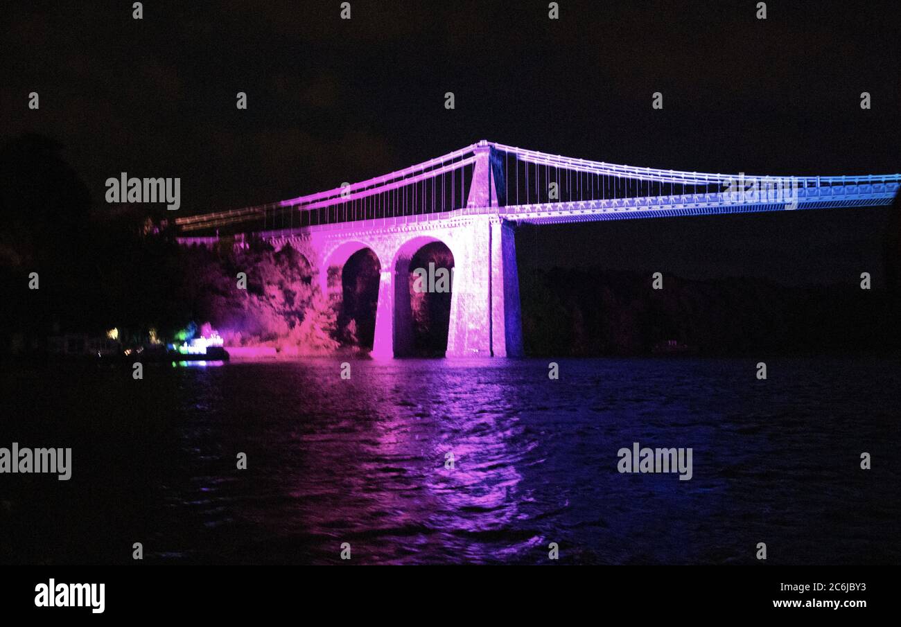 Bangor, Gwynedd, N pays de Galles. Suspension de Menai le pont au-dessus du détroit de Menai est illuminé dans des couleurs arc-en-ciel pour célébrer 72 ans du NHS Banque D'Images