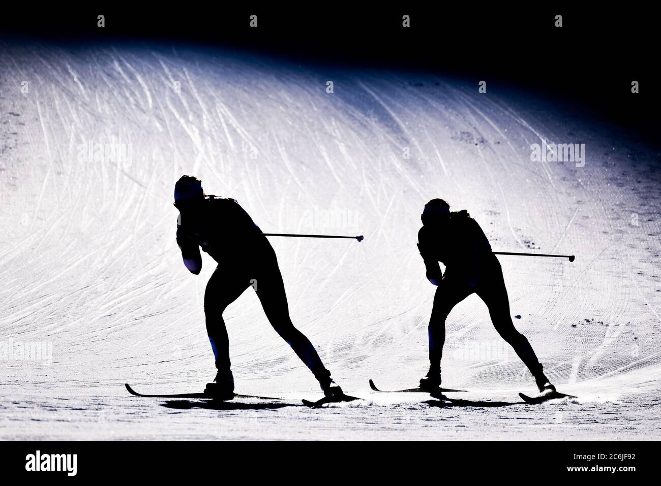 Les concurrents qui ont fait un sprint aux Championnats du monde de ski nordique 2019 de la FIS à Seefeld, en Autriche, sont silhouetés lorsqu'ils se tournent au bas de la colline. Banque D'Images