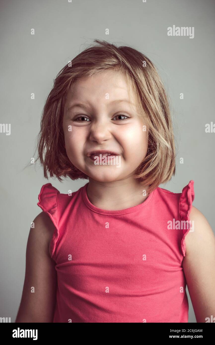 blonde caucasienne petite fille faisant un visage laid et drôle. studio portrait Banque D'Images