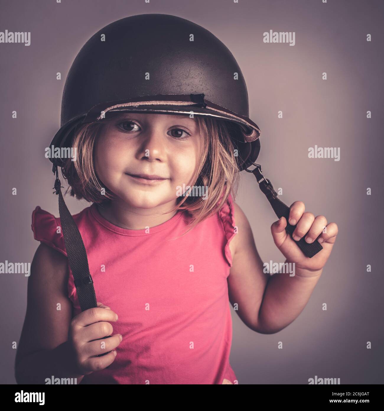 Petite fille caucasienne portant un casque militaire. Portrait de stidio Banque D'Images