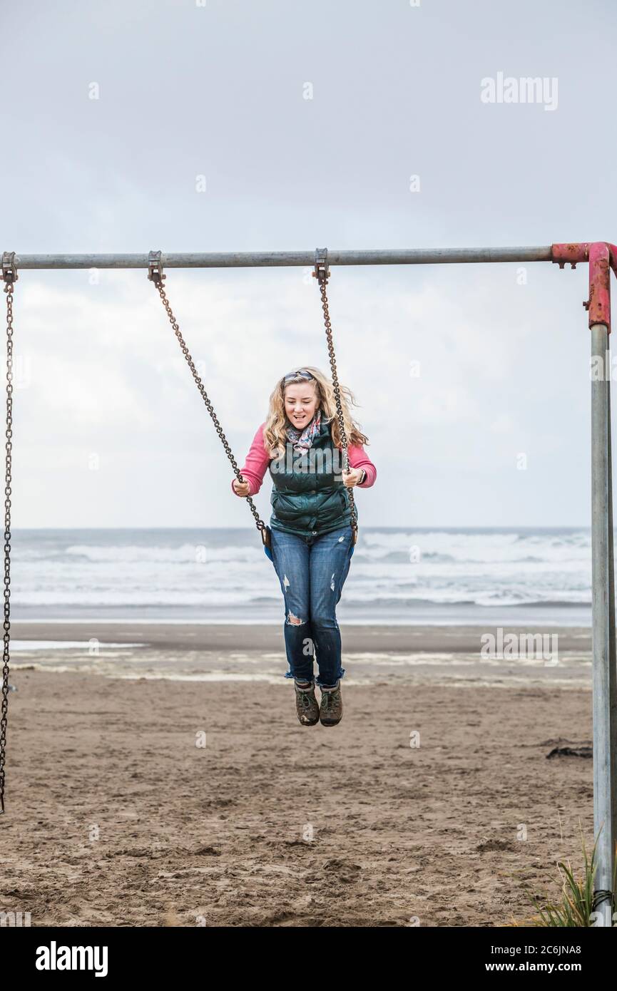 Une femme d'âge moyen se balançant sur une balançoire sur Seaside Beach, Oregon, États-Unis. Banque D'Images