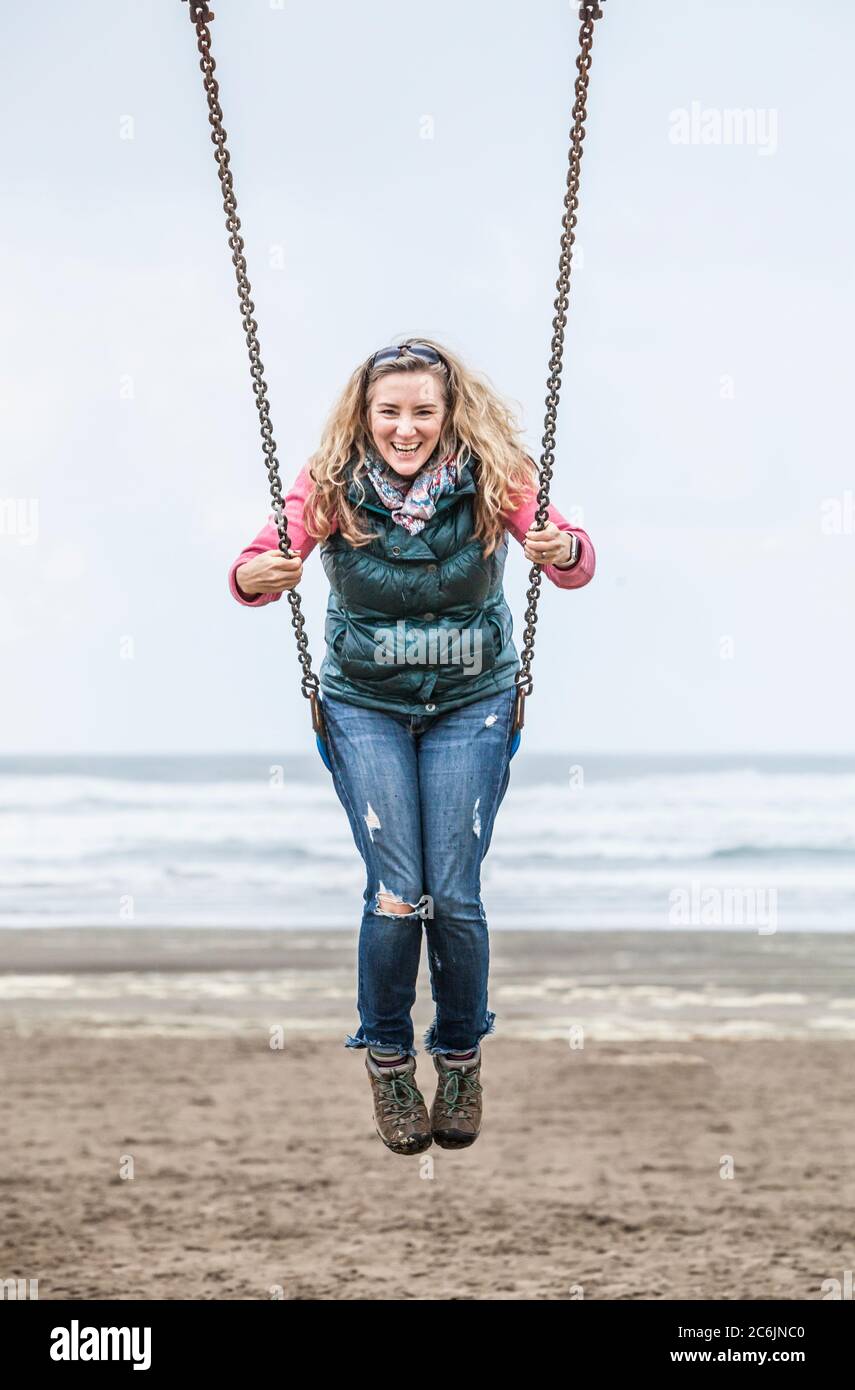 Une femme d'âge moyen se balançant sur une balançoire sur Seaside Beach, Oregon, États-Unis. Banque D'Images