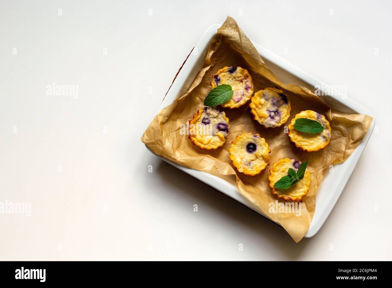 Muffins maison au fromage cottage avec myrtilles dans un plat sur fond blanc. plat, espace copie Banque D'Images