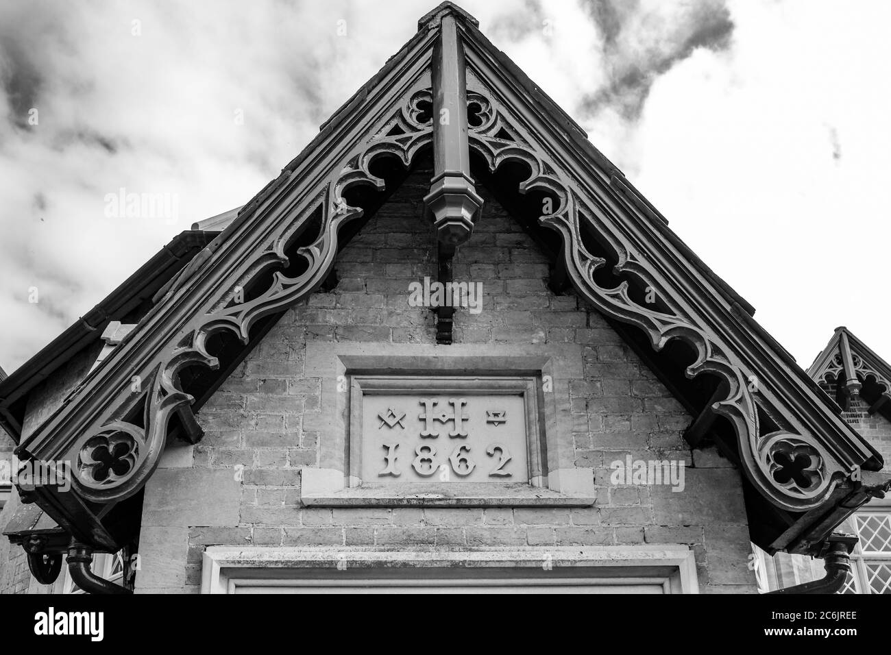 Vue monochrome détaillée d'une ancienne maison en pierre montrant le détail de la toiture avec une sculpture en brique à la date de la construction. Banque D'Images