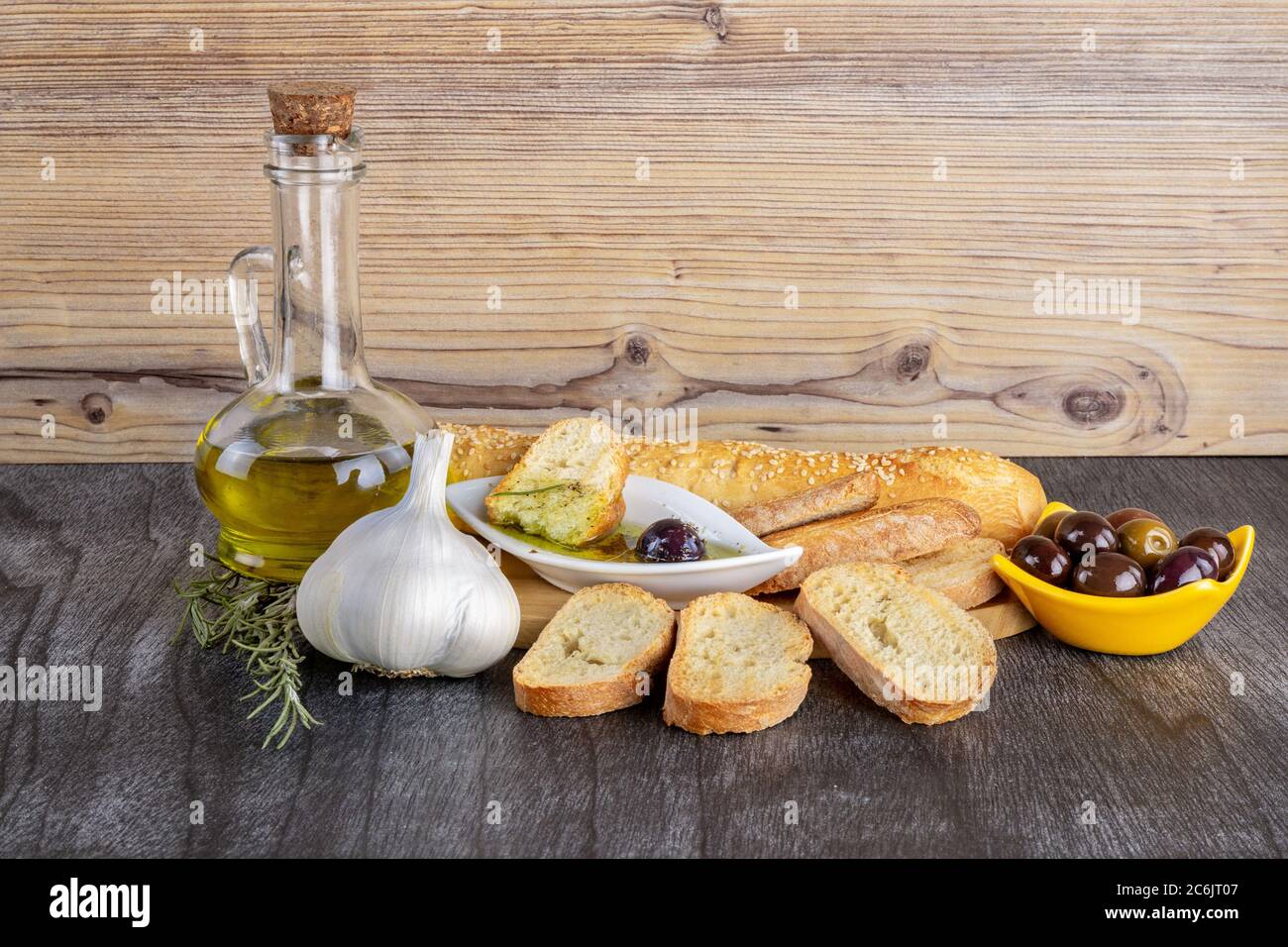 Le pain trempé dans l'huile d'olive avec de l'olive. Sauce à l'huile d'olive grecque. Sauce grecque dans un bol blanc et olives grecques sur fond de bois. Huile d'olive et épices Banque D'Images