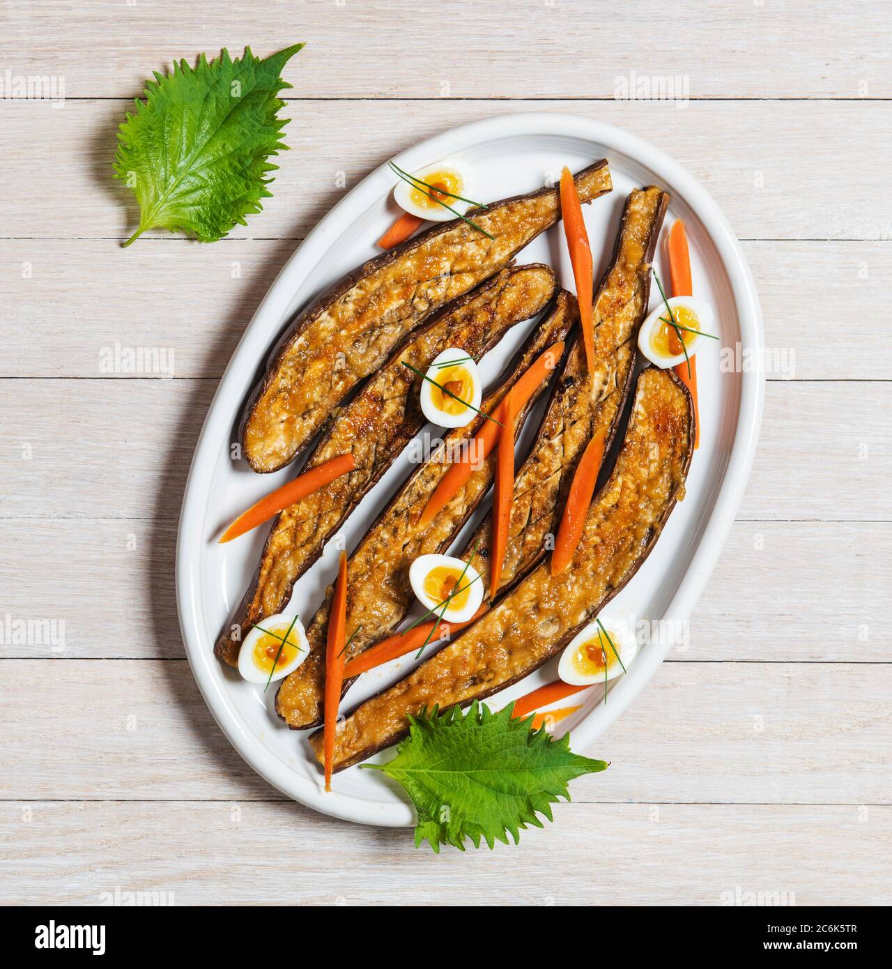 Eggi japonais rôti de miso garni d'œufs de caille, de lances à épi de bougeonneau, de ciboulette et de feuilles de ciso Banque D'Images