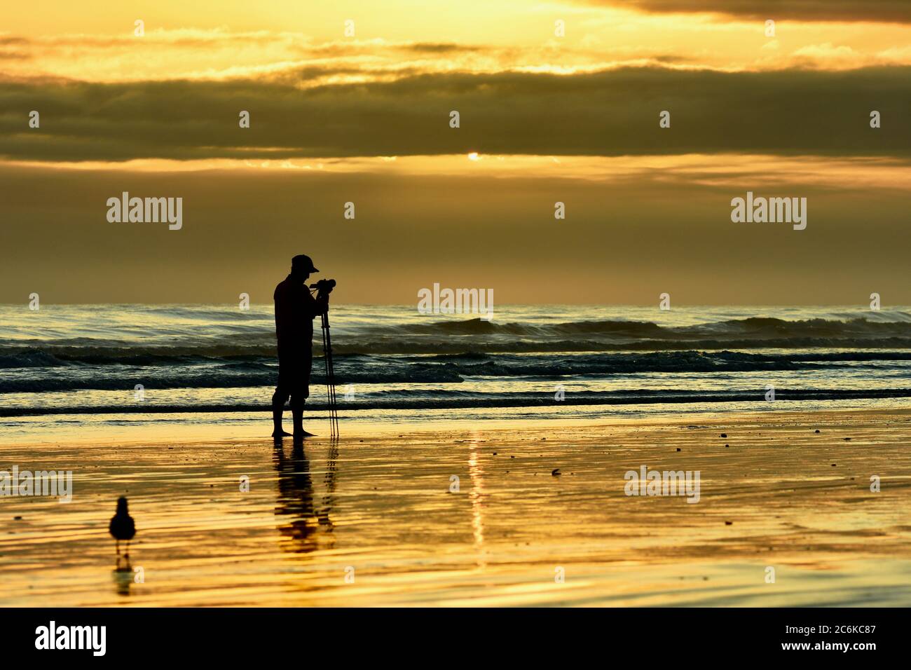 Un photographe non identifié prenant des photos d'un coucher de soleil sur la mer Banque D'Images