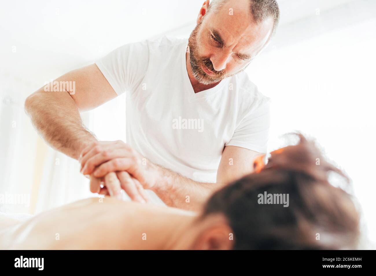 Homme de masseur barbu effectuant des manipulations de massage sur la zone de Scapula pendant le massage de corps de jeune femme. Banque D'Images