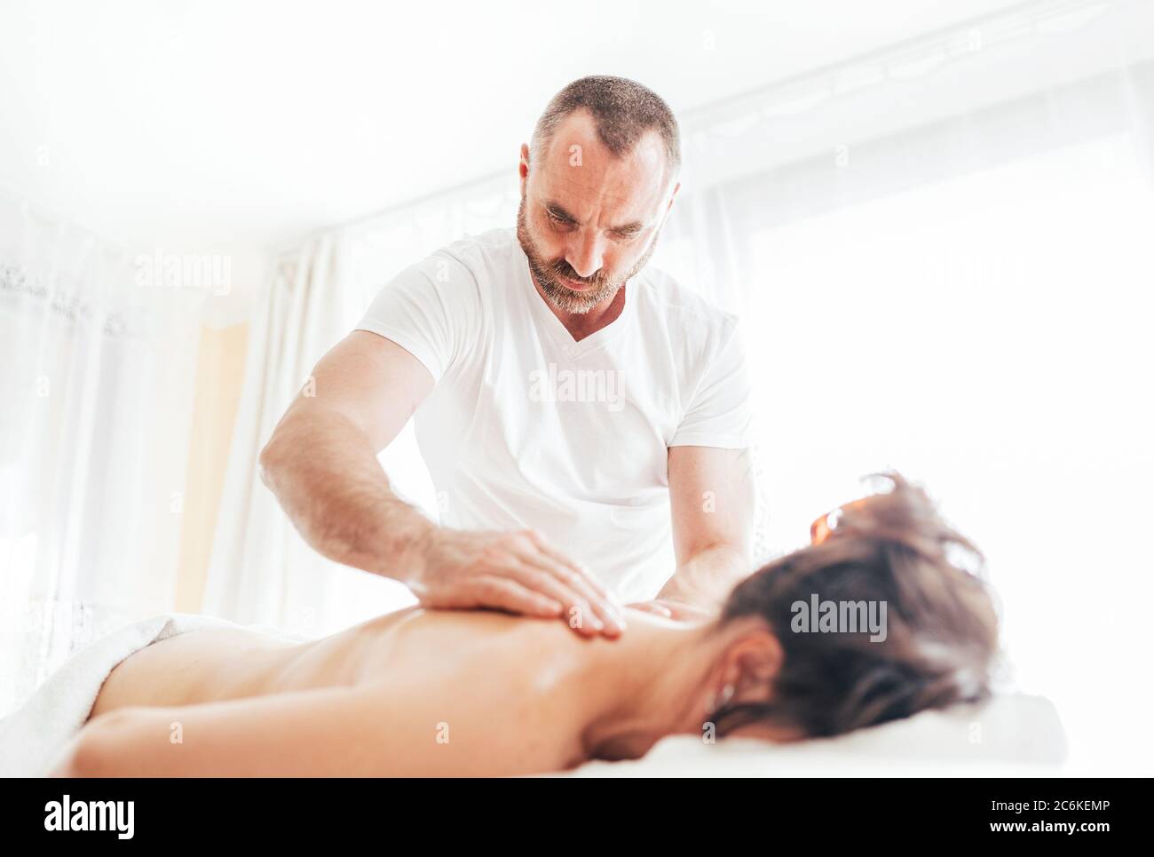 Homme de masseur barbu effectuant des manipulations de massage sur la zone de Scapula pendant le massage de corps de jeune femme. Banque D'Images