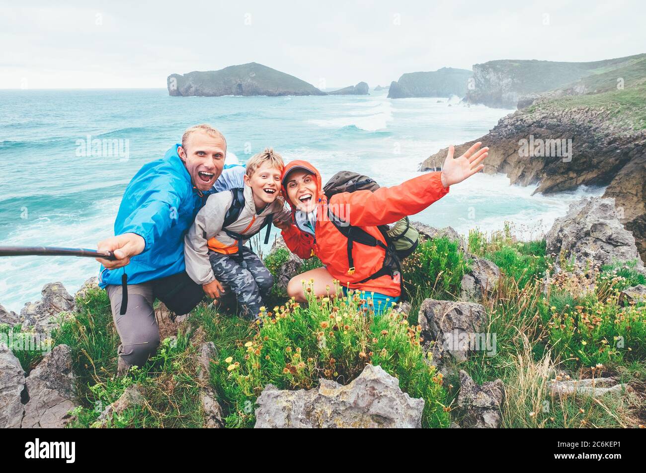 Voyageurs heureux deux parents de famille avec leur petit fils sur la côte de mer de Cantabrie posant joyeusement dans la caméra en allant à Camino de Santiago Banque D'Images